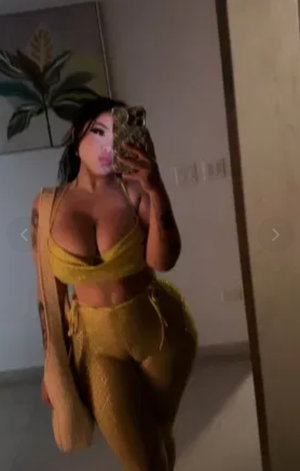 Woman in yellow outfit taking mirror selfie indoors.