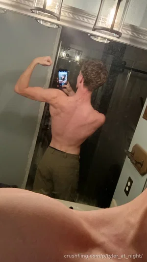 Man with muscular back flexing in mirror selfie, wearing pants, in bathroom.