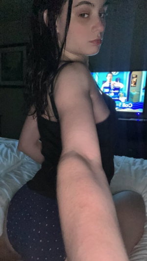 Curvy woman in black top taking bedroom selfie