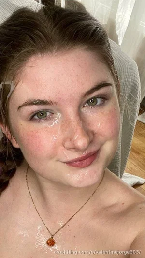 Woman with freckles and green eyes, topless, wearing necklace, indoors.
