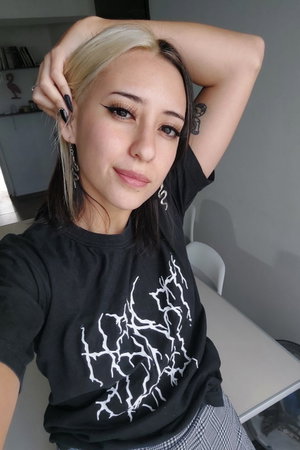 Woman with two-tone hair in black t-shirt taking indoor selfie.