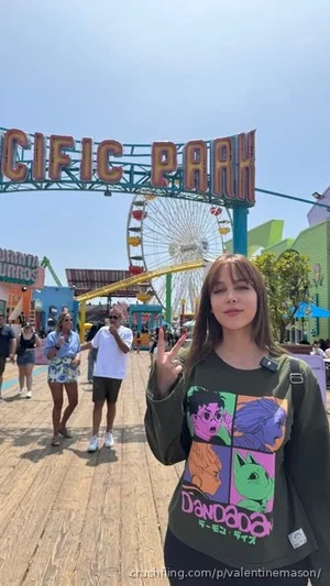 Woman in green graphic tee and black pants posing at Pacific Park amusement park.