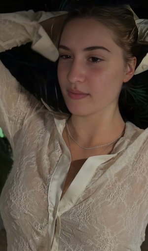 Woman in white lace top lying down, arms raised, indoor setting.