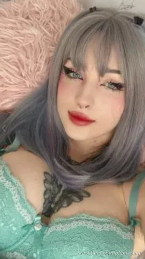 Woman with gray hair and green lace top lying on pink fluffy surface.