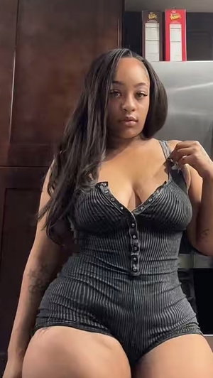 Woman with long dark hair in striped romper indoors.