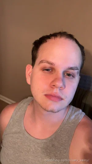 Man in gray tank top, indoor selfie, neutral expression, short hair.
