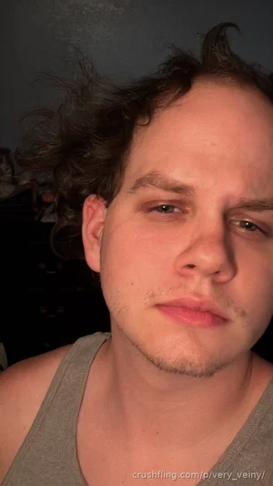 man with messy dark hair wearing gray tank top indoors
