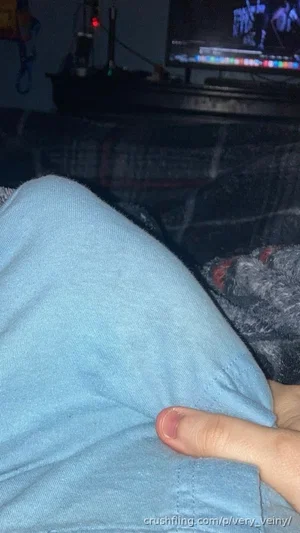 Person in light blue fabric, hand visible, sitting on patterned surface near TV.