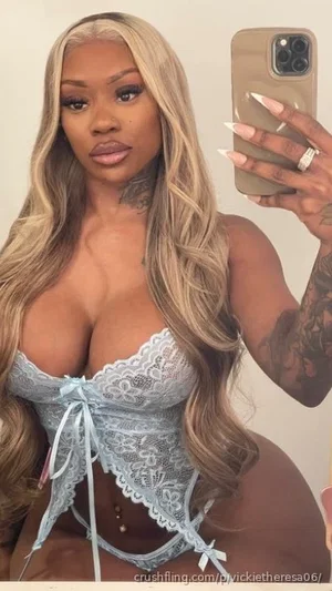 Woman with long blonde hair in light blue lace lingerie, holding phone for mirror selfie.
