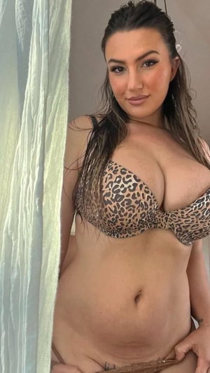 Curvy woman in leopard print bra taking indoor selfie.