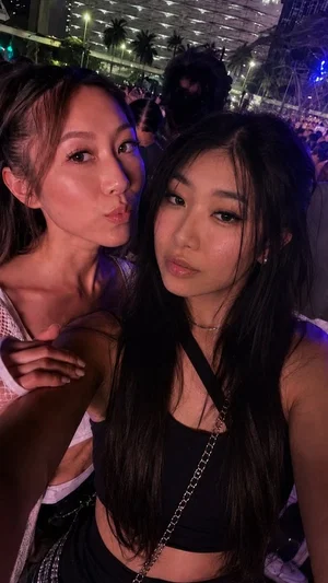Two Asian women in crop tops at a crowded outdoor event at night.