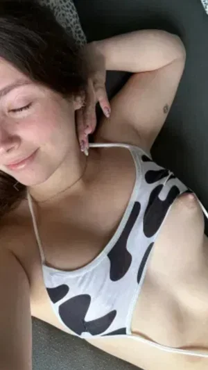 Woman with dark hair in cow-print top lying down, hand behind head.