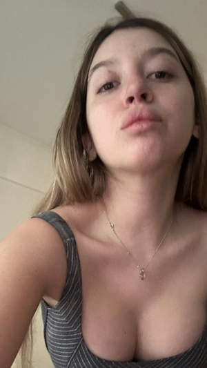 Woman with light brown hair in striped top taking selfie indoors.