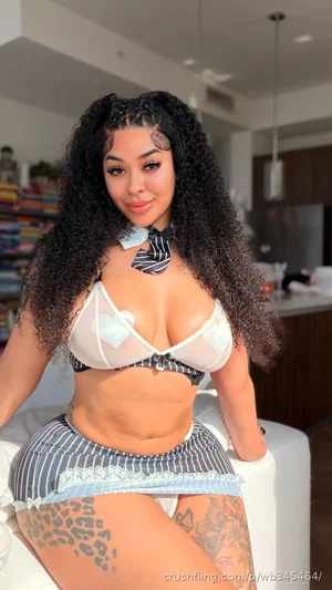 Woman with curly hair in striped lingerie posing indoors.