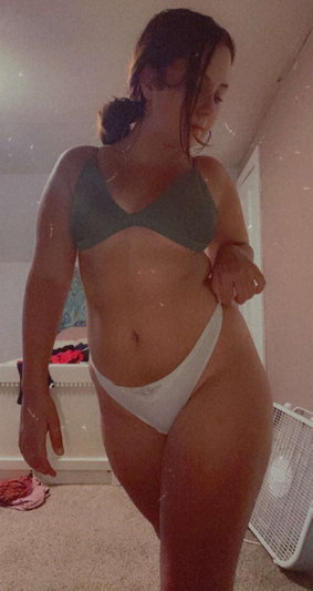 Woman in green bra and white underwear posing in a room with wet skin.