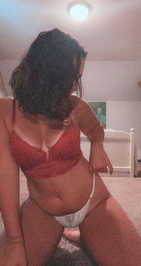Woman in red bra and white underwear posing in bedroom.