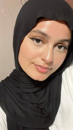 Woman in black hijab taking close-up selfie indoors.