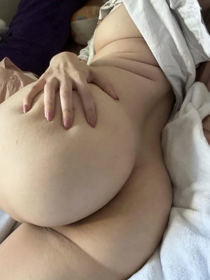 Curvy person lying in bed with hand on hip.