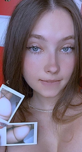 Woman with long brown hair holding polaroid photos indoors.