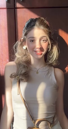 Woman with blonde wavy hair in beige top indoors.