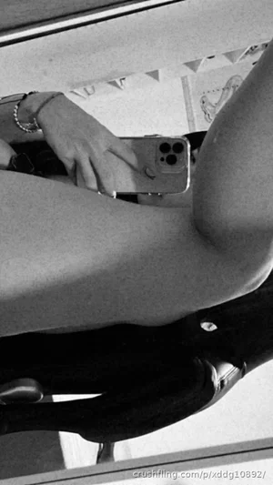Woman in black pants holding phone, sitting indoors, legs visible.