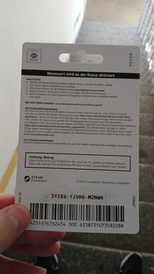 Hand holding Steam gift card with text and barcode.