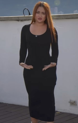 Woman with long reddish hair in black dress on balcony.