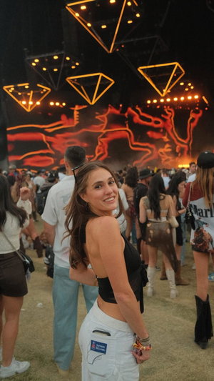 Woman in black top and white pants at outdoor festival.