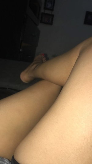Woman's bare legs crossed indoors with red toenails.