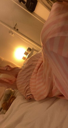Person in pink striped pajamas lying on bed, indoor setting.