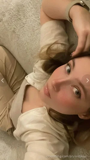 Woman with light brown hair lying on a fluffy surface, wearing a light-colored button-up shirt.