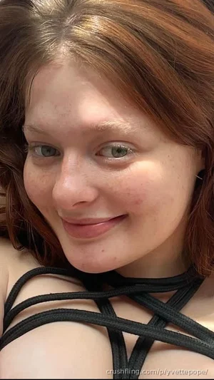 Woman with brown hair and green eyes wearing black strappy top, close-up selfie.