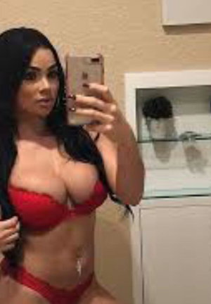 Woman in red lingerie taking mirror selfie indoors.
