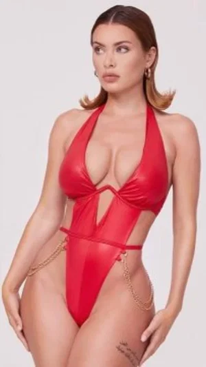 Woman in red halter swimsuit with side cutouts and gold chains, posing against white background.